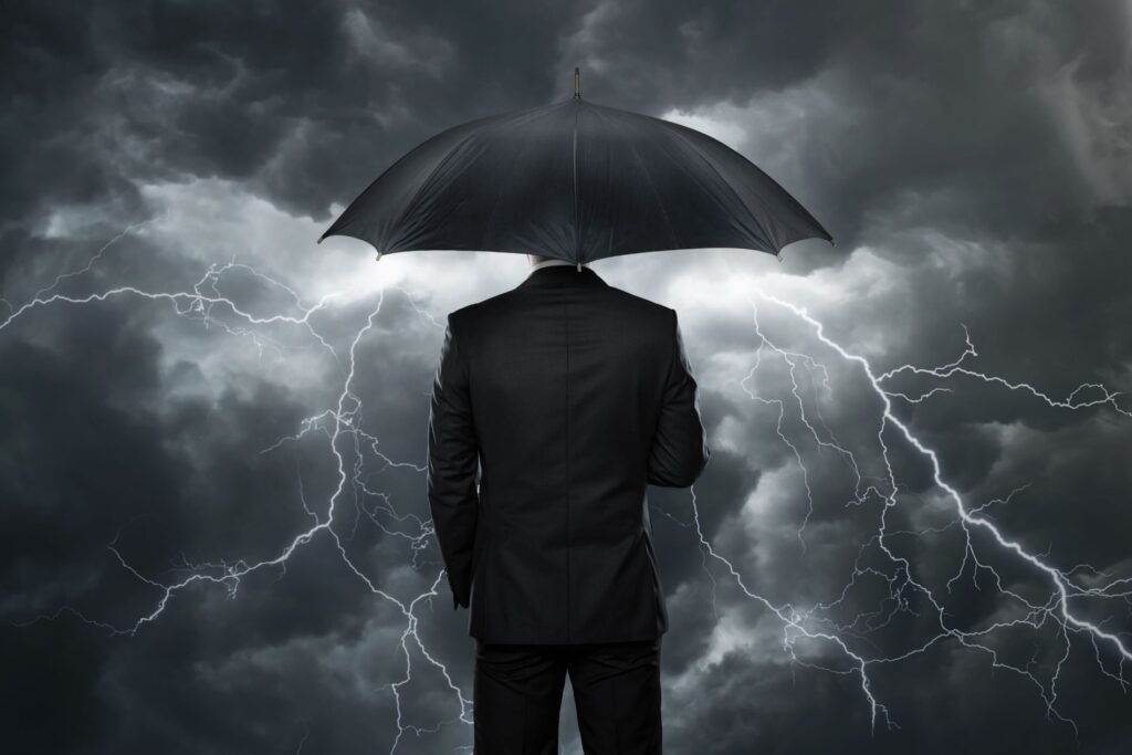 Man holding an umbrella weathering a storm with business consulting services